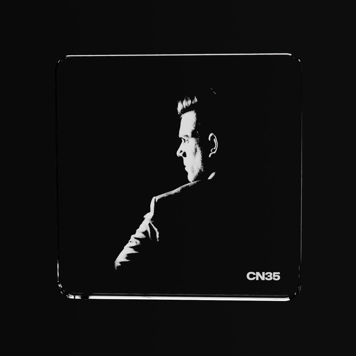 A CN35 crystal slide engraved with a portrait, glowing on black